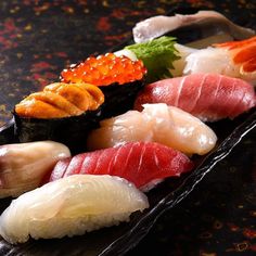 an assortment of sushi on a black plate