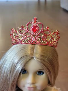 a doll with blonde hair wearing a red tiara on top of it's head