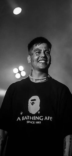 a black and white photo of a man with piercings on his head, wearing a bathing ape t - shirt