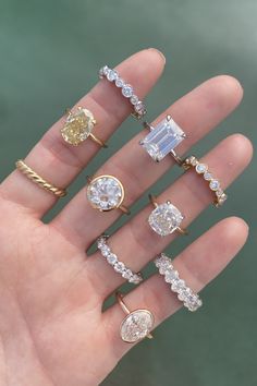 a person's hand with five different rings on it, including an engagement ring