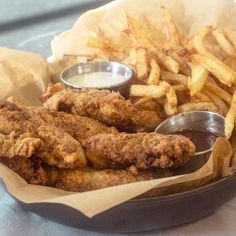 fried chicken and french fries in a basket with dipping sauce