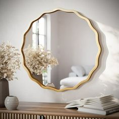 a mirror sitting on top of a wooden table next to a vase with flowers in it