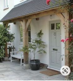 a small white house with a porch and potted plants