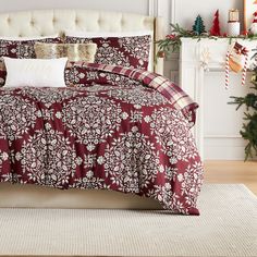 a bed with red and white comforter next to a christmas tree