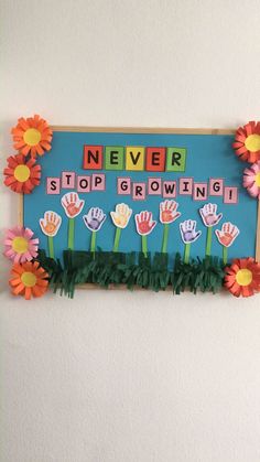 a sign that says never stop growing with flowers and handprints on the letters