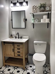 a white toilet sitting next to a sink in a bathroom under a mirror above a wooden cabinet