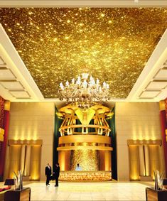 two people standing in front of a large chandelier with gold stars on the ceiling