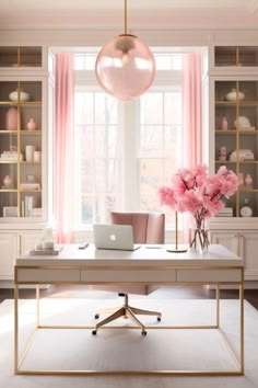 a desk with a laptop on it in front of a window and shelves filled with pink flowers