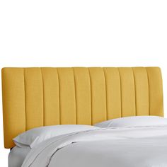 an upholstered yellow headboard with white sheets