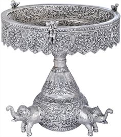 an ornate silver bowl with two elephants on the bottom and one elephant in the middle