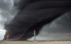 a large black cloud is in the sky above power lines and an electrical pole with wires running through it