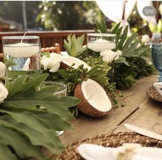 a wooden table topped with lots of white flowers and greenery on top of it