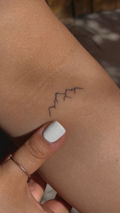 a woman's arm with a small heartbeat tattoo on the left side of her leg