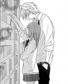 a man and woman standing next to each other in front of a bookshelf