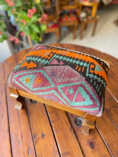 a wooden bench with a colorful cushion on it