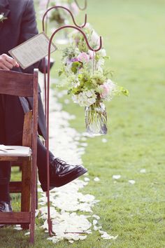 a person sitting in a chair holding a book and flower arrangement on the back of it