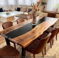 a large wooden table surrounded by chairs and couches in a living room with lots of windows