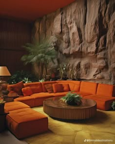 a living room with orange couches and large rocks on the wall behind it, as well as a round coffee table