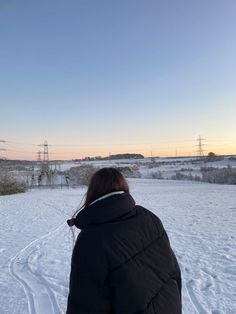 a woman standing in the snow with her back turned to the camera, looking at power lines