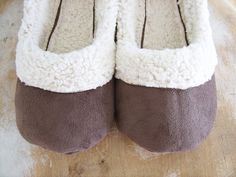 a pair of brown and white slippers sitting on top of a wooden floor