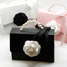 three bags with flowers and pearls on them sitting next to each other in front of a pink box