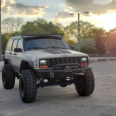 a white jeep parked in a parking lot with the sun shining down on it's headlamps