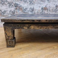 an old coffee table with wooden legs on a wood floor in front of a wall