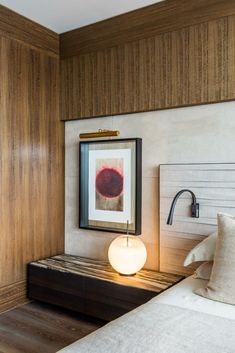 a bedroom with wood paneling and white bedding has a framed painting on the wall