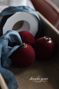 two red apples sitting on top of a wooden table next to a roll of tape