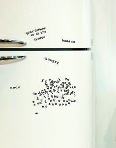 a white refrigerator freezer sitting inside of a kitchen next to a wall with writing on it