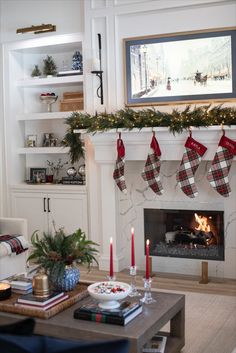 a living room decorated for christmas with stockings hanging over the fire place and candles on the mantle