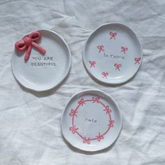 three white plates with pink bows and words on them