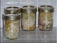 four jars filled with food sitting on top of a white tiled counter next to each other