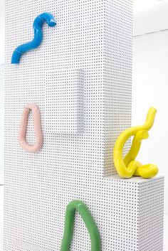 three different colored objects are on the wall in front of a white perfored background