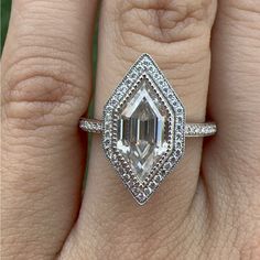 a woman's hand with an engagement ring on it, and the center stone is surrounded by diamonds