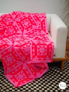 a couch with a pink quilt on it and a black and white checkered floor