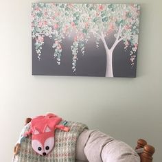 a stuffed animal is sitting on a chair in front of a wall with a painting