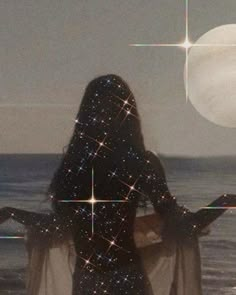 a woman standing in front of the ocean with her back to the camera looking at stars