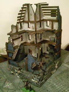 a model of a house made out of wood and cement blocks on top of a table