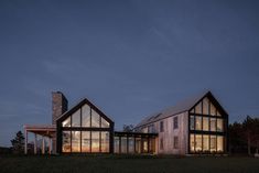 two large windows on the side of a house at night with trees in the background