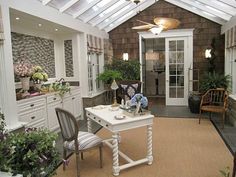 a living room filled with furniture and lots of plants on top of the tables in front of them