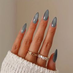 a woman's hand with grey and white nail polish on it, wearing a sweater