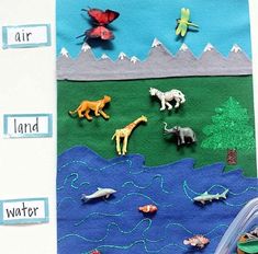 an art project with animals, water and land on the side of a white wall