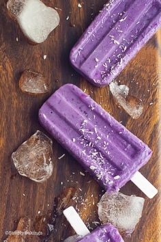 three popsicles with purple icing on top of ice and some pieces of wood