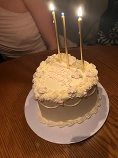 a birthday cake with three lit candles on it