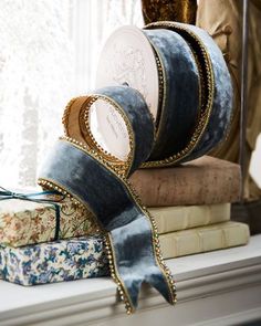 a stack of blue ribbon sitting on top of a window sill next to a statue