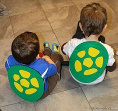 two young boys sitting on the floor with stuffed animals in their laps and looking at each other