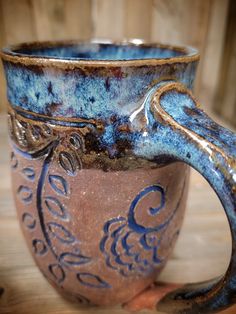 a blue and brown cup sitting on top of a wooden table