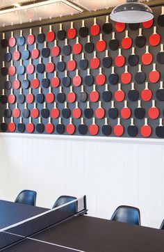 a ping pong table in front of a wall with red and black circles on it