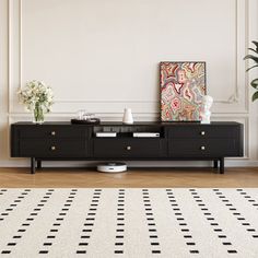 a black and white rug in front of a tv stand with two vases on it